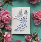 A papercut greetings card with a 3D butterfly and cut out flowers