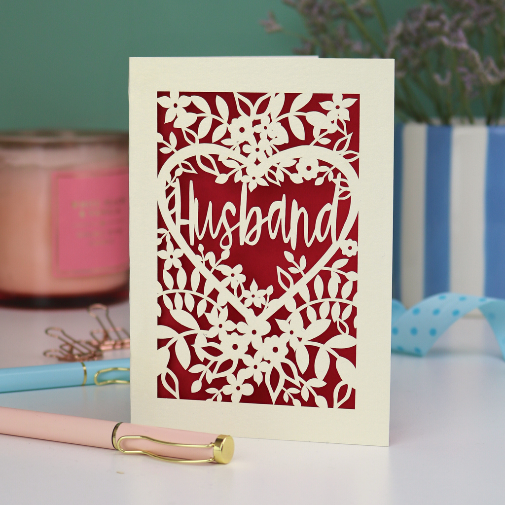 A laser cut husband valentines card with floral design on a green background
