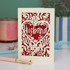 A laser cut husband valentines card with floral design on a green background