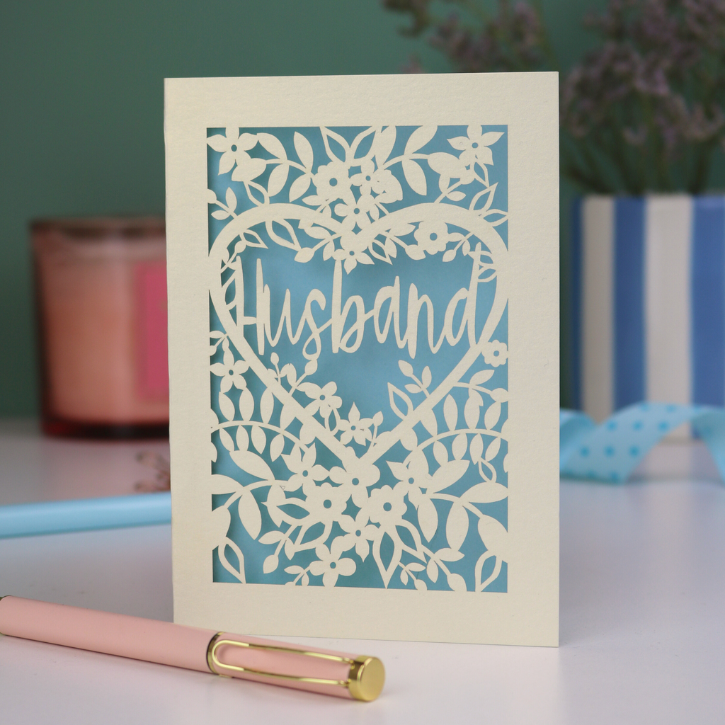 A laser cut husband valentines card with floral design on a green background