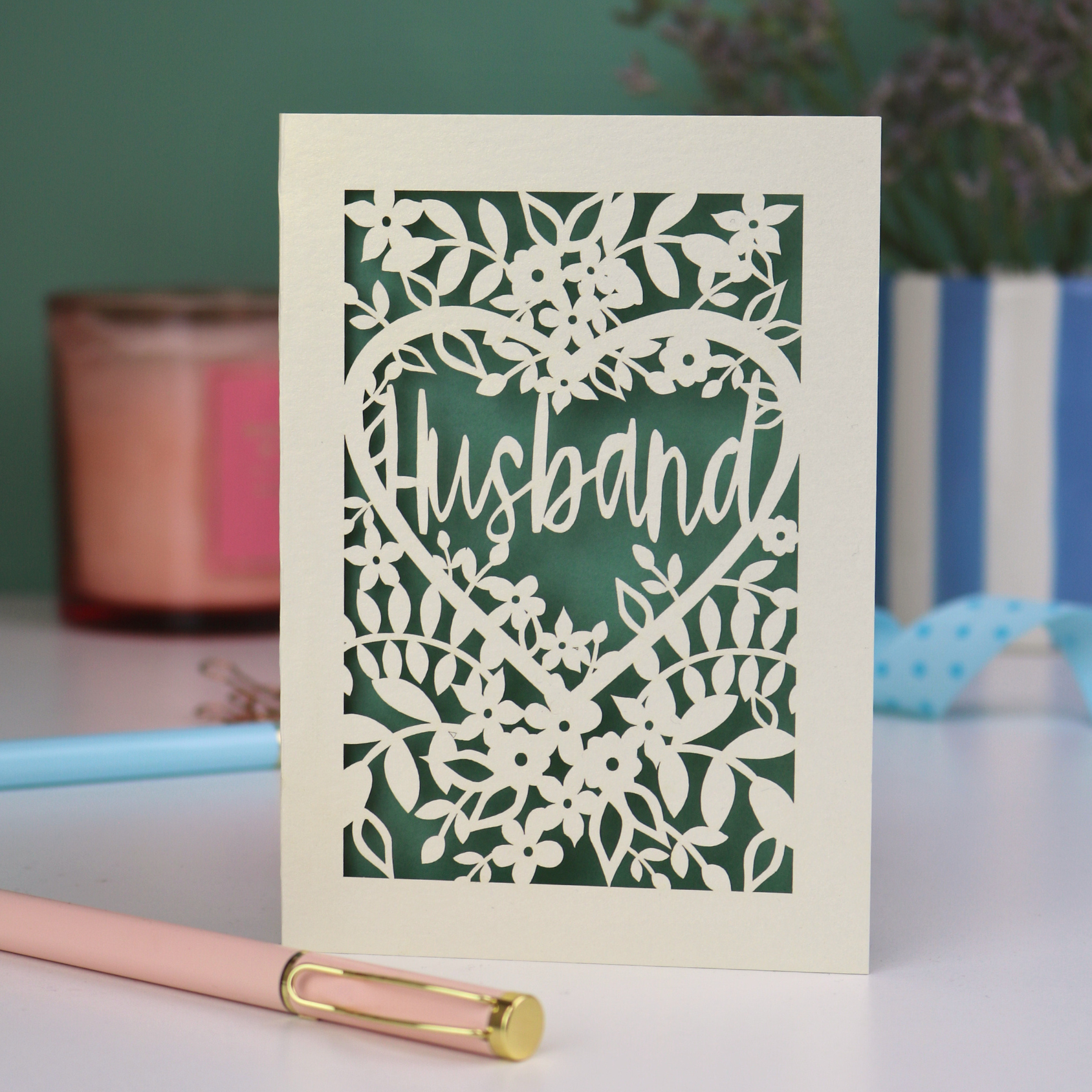 A laser cut husband valentines card with floral design on a green background