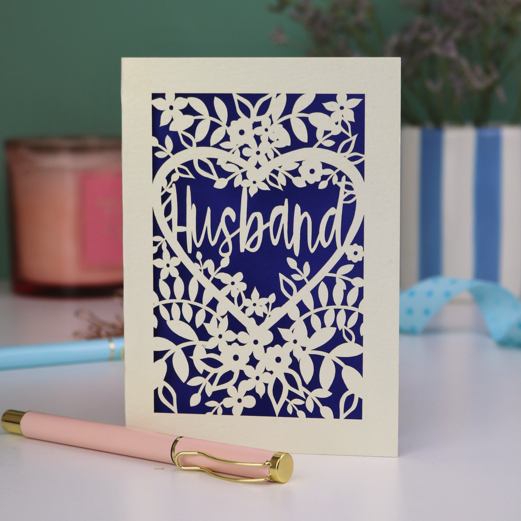 A laser cut husband valentines card with floral design on a green background