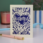 A laser cut husband valentines card with floral design on a green background