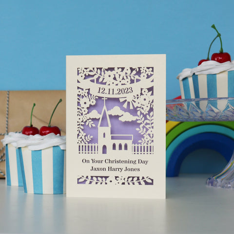 A laser cut card with a banner at the top with a date. There is a church shape in the centre of the card and text underneath. Text says "On Your Christening Day" and on another line, "Jaxon Harry Jones" - A6 (small) / Lilac