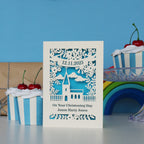 A cream and blue card for Christenings. Cut away card reveals blue paper behind and forms the shape of a church and flowers. Cut away text has the date at the top, "On Your Christening Day" and the name at the bottom.