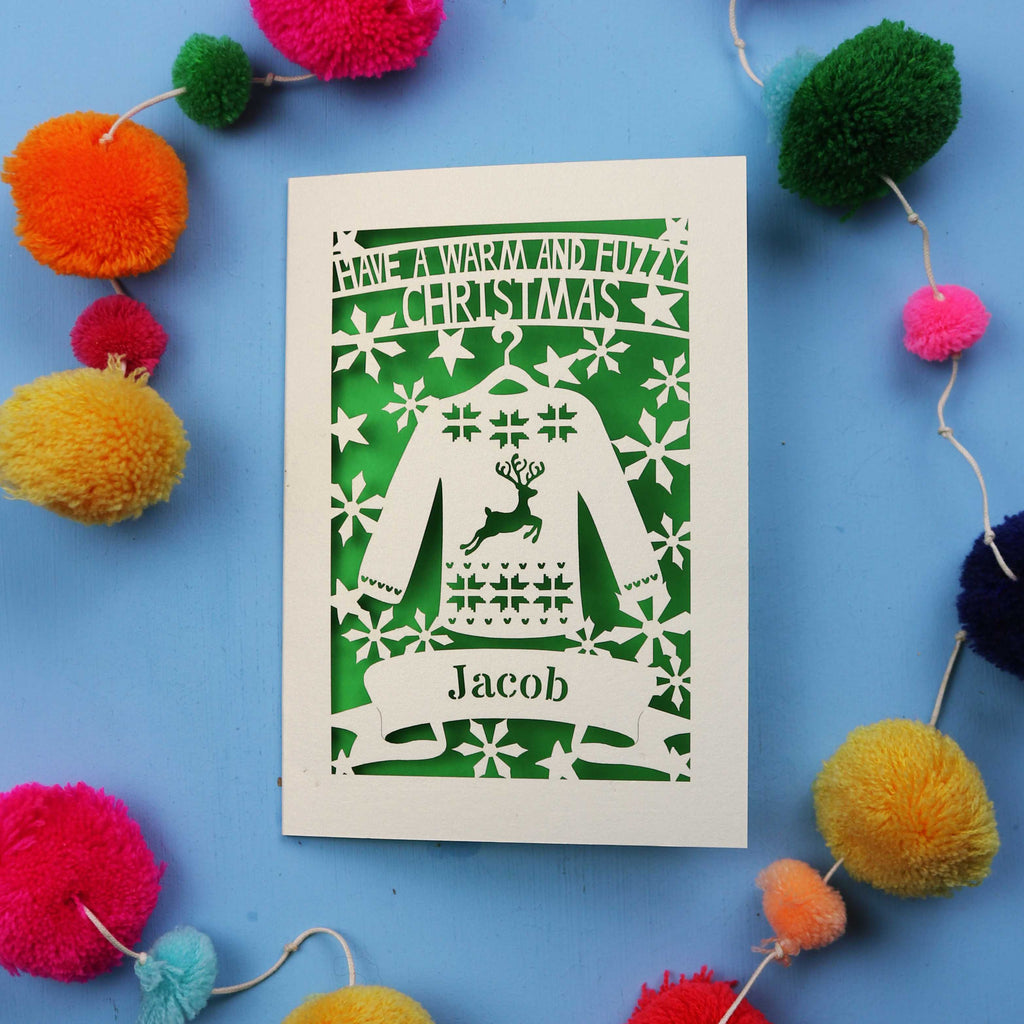 Unique Christmas card with festive Christmas jumper design on a blue background with colourful pom-poms.