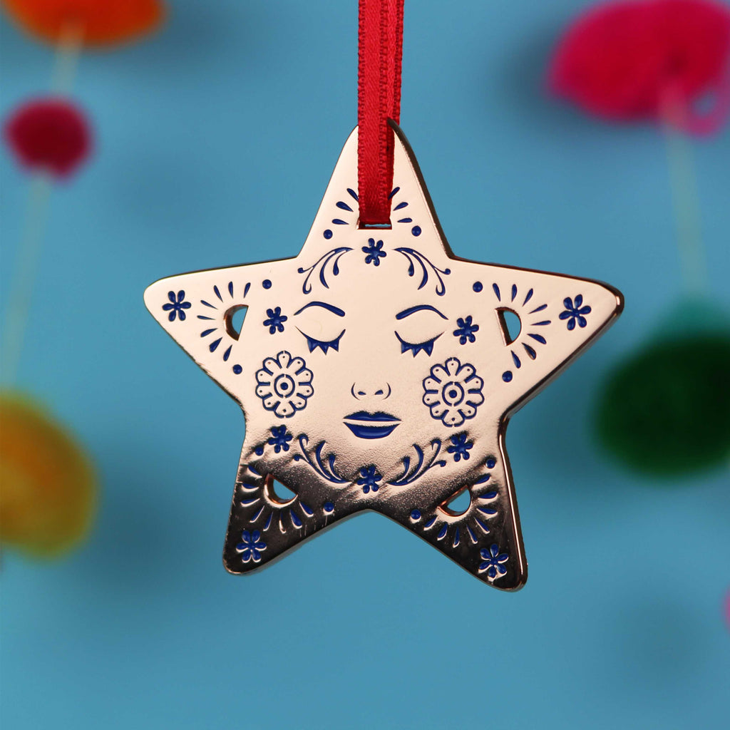 Decorative star Christmas ornament with face design on a blue background