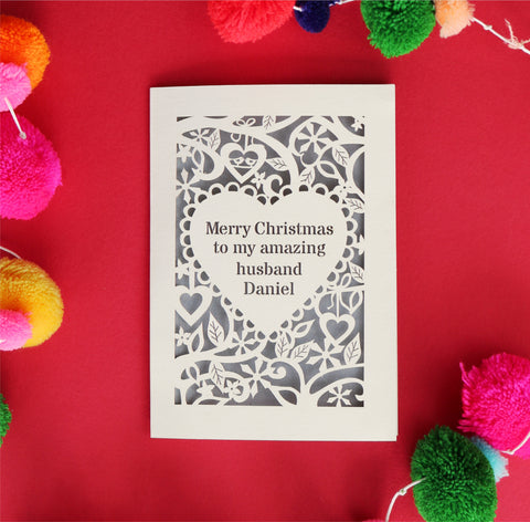 A personalised Christmas card with text in a heart surrounded by a floral border. Text reads "merry Christmas to my amazing husband Daniel"