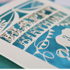 A laser cut birthday card with circus big top design, "Happy Birthday" and a name, with an age cut out.