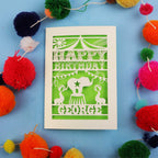Personalised Circus Birthday card with 'Happy Birthday George' text on a blue background with colourful pom-poms.