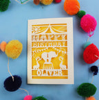 1st Birthday card with cut-out design on a blue background with colourful pom-poms