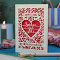 Anniversary card with decorative heart design on a table with stationery items.