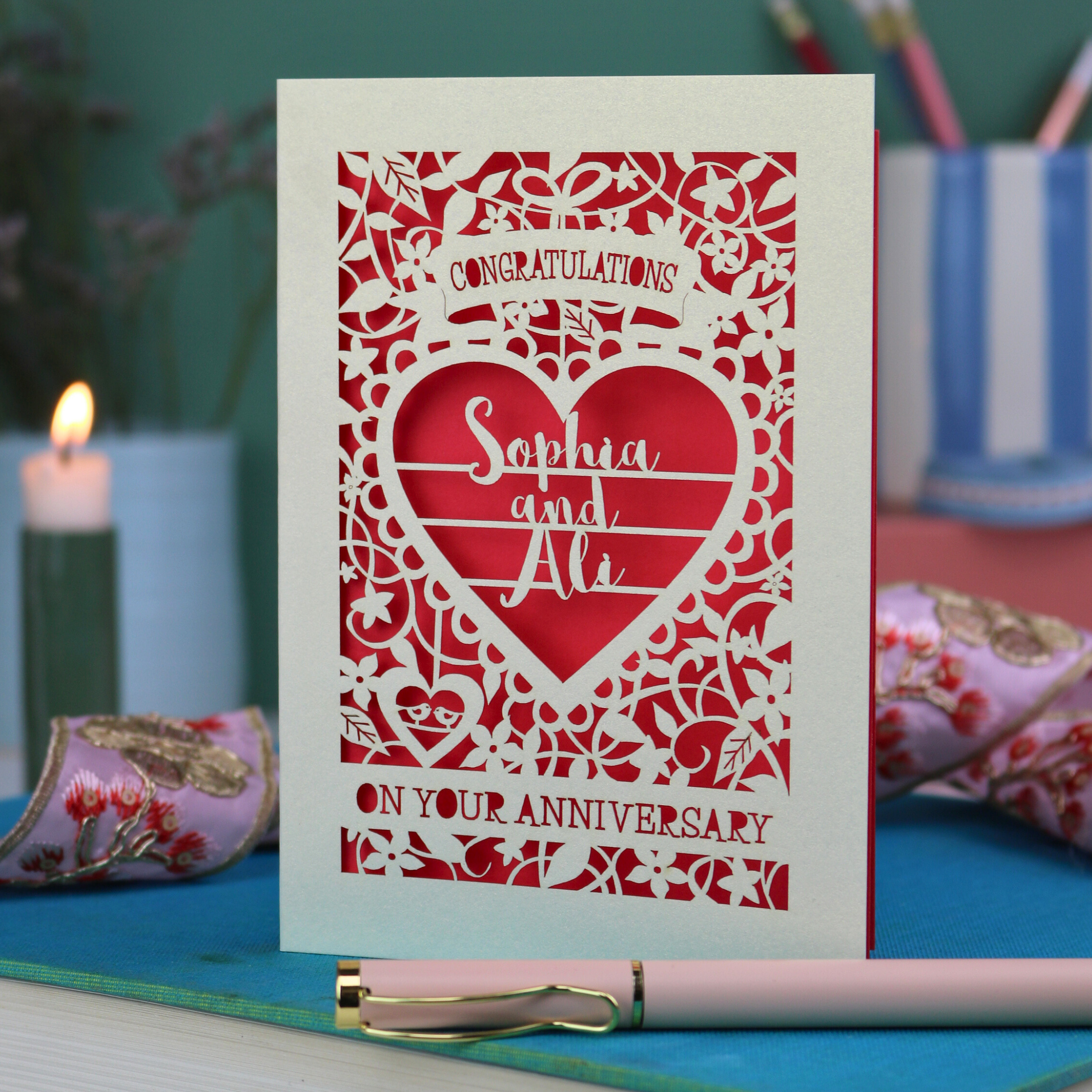 Anniversary card with decorative heart design on a table with stationery items.