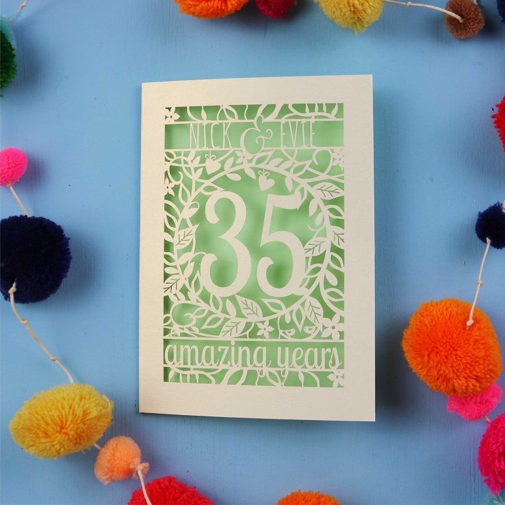 Papercut Coral anniversary Card with '35 amazing years' on a blue background with colourful pom-poms