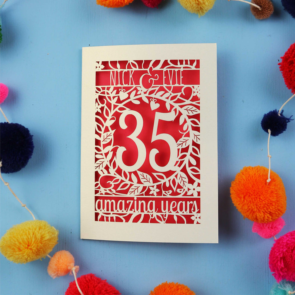 Coral anniversary Card with '35 amazing years' on a blue background with colourful pom-poms