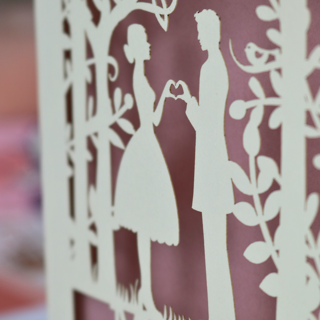  cut-out of a couple holding hands with a heart shape against a blurred background