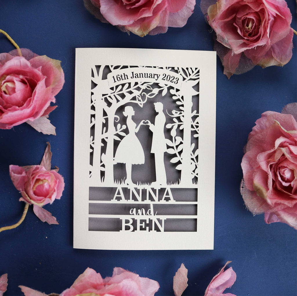 A personalised engagement card that features the silhouettes of a couple, and is personalised with a date in a banner at the top and the names of the couple over three lines of text at the bottom