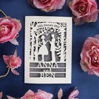 A personalised engagement card that features the silhouettes of a couple, and is personalised with a date in a banner at the top and the names of the couple over three lines of text at the bottom