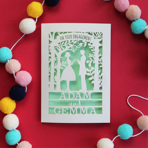 Papercut engagement cards with the silhouettes of a man and woman surrounded by trees and leaves. Card says "On your engagement" and is personalised with their names - A5 / Light Green