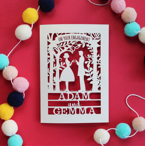 A laser cut personalised engagement card with cut out silhouettes of a couple and the words "On your engagement" with names underneath - A5 / Bright Red