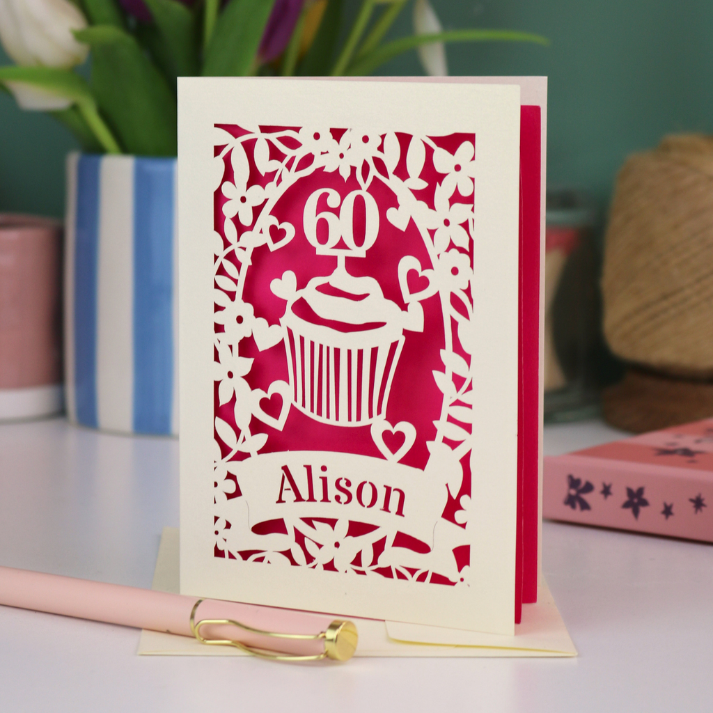 A personalised 60th birthday card with laser cut cupcake design and the age '60', with the name 'Alison' cut out of a banner in a laser cut stencil font
