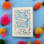 Decorative birthday card with '50' and 'Carla' on a blue background with colourful pom-poms.