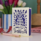 A cream and violet laser cut 60th birthday card with cupcakes on a cake stand design, the number '60' and "Happy Birthday Jenny" personalised text in cut out stencil lettering