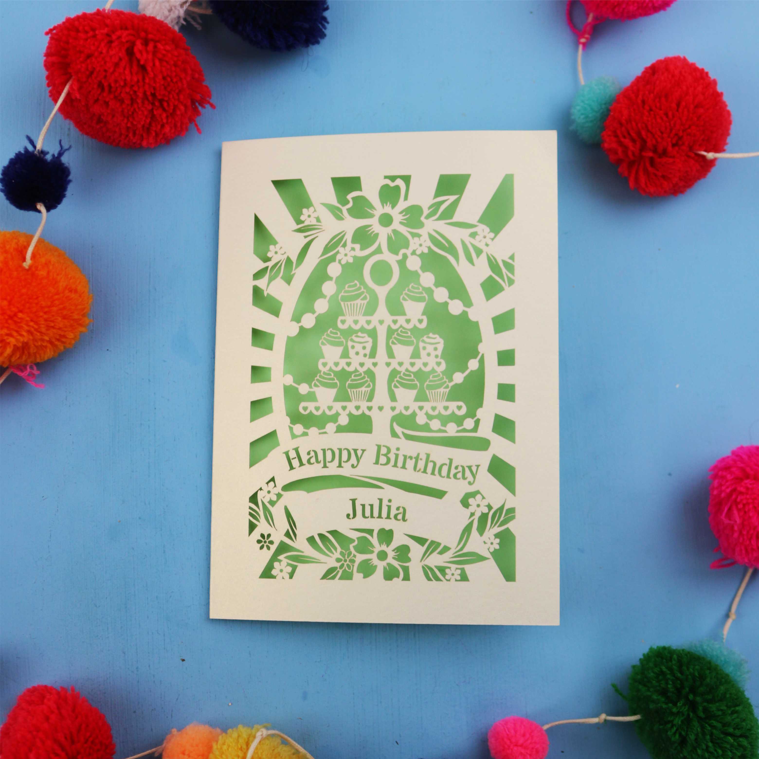 Personalised laser cut birthday card with decorative elements on a blue background with colourful pom-poms.