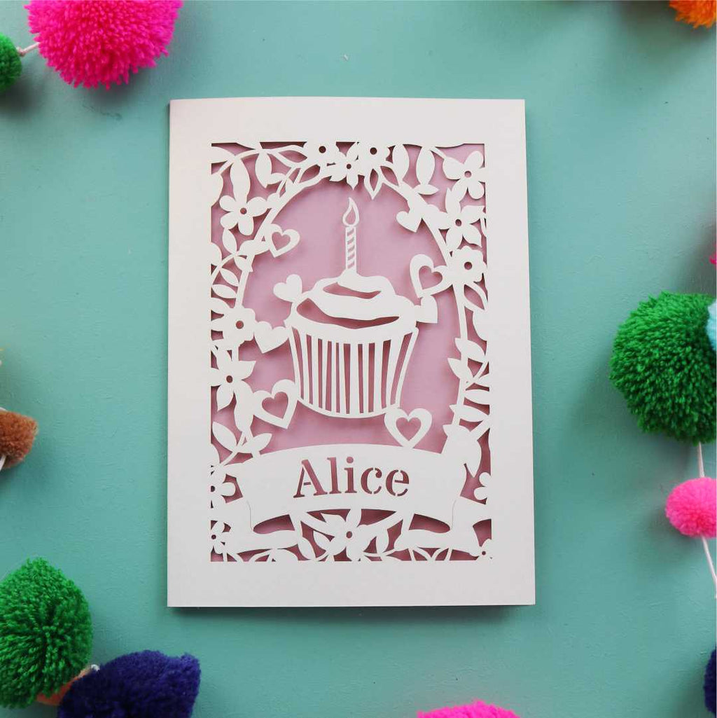 A laser cut birthday card with a cupcake and candle . Card is personalised with a first name