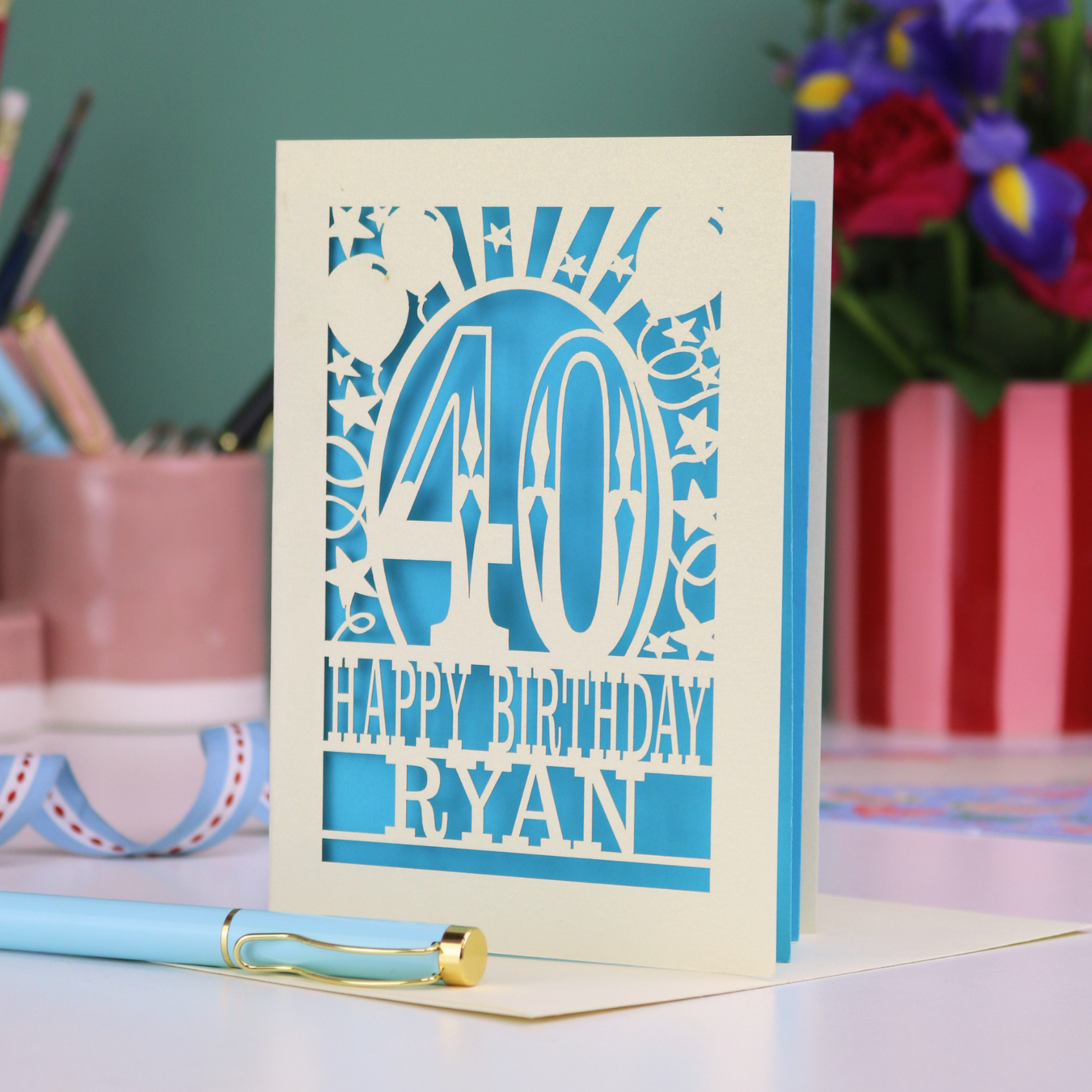 Personalized 40 birthday card with '40 Happy Birthday Ryan' on a desk with stationery items.