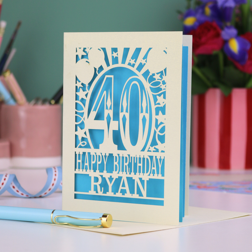 Personalized 40 birthday card with '40 Happy Birthday Ryan' on a desk with stationery items.