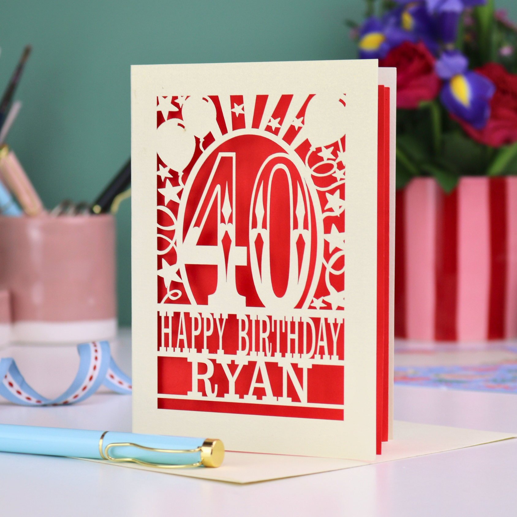 Personalized 40 birthday card with '40 Happy Birthday Ryan' on a desk with stationery items.