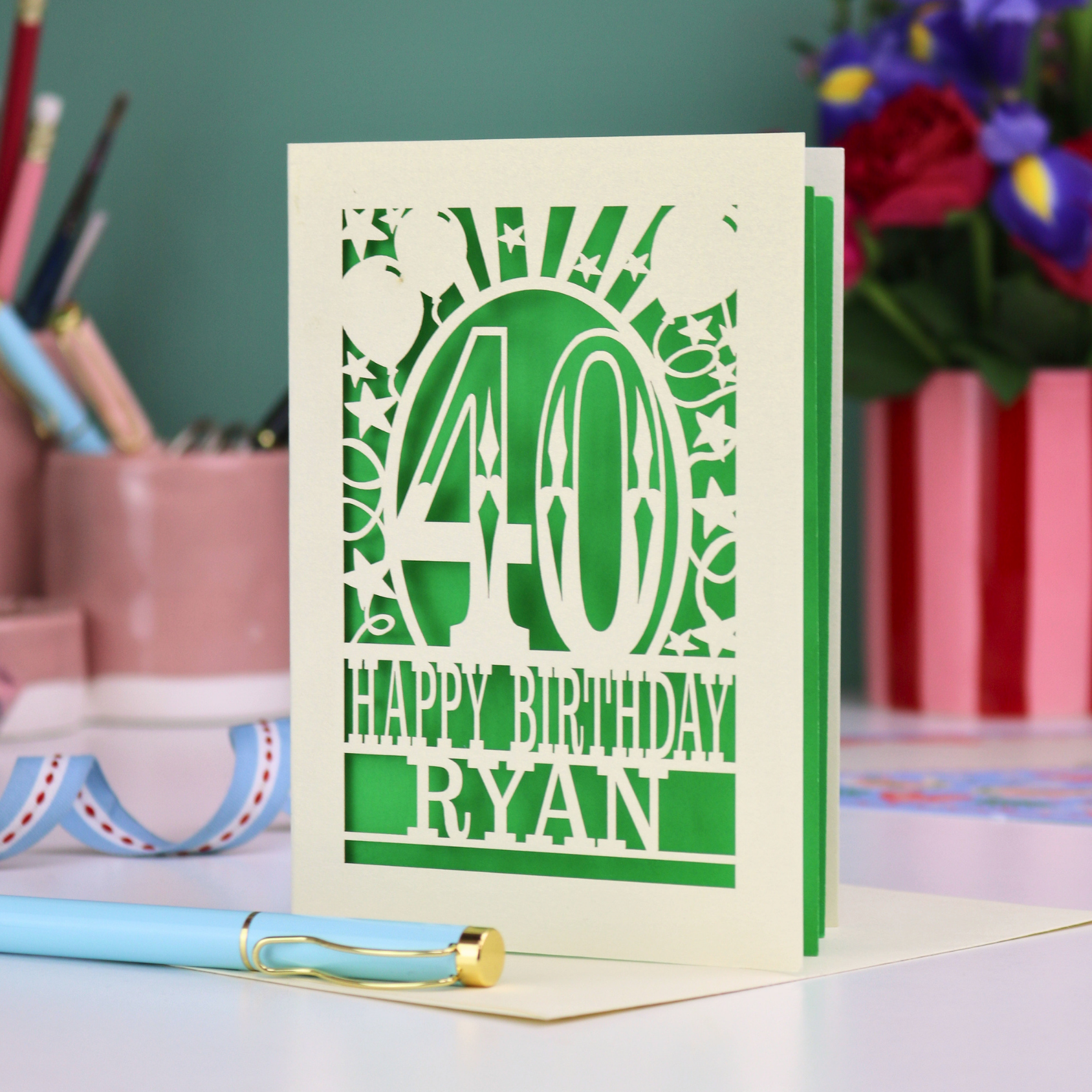 Personalized 40 birthday card with '40 Happy Birthday Ryan' on a desk with stationery items.