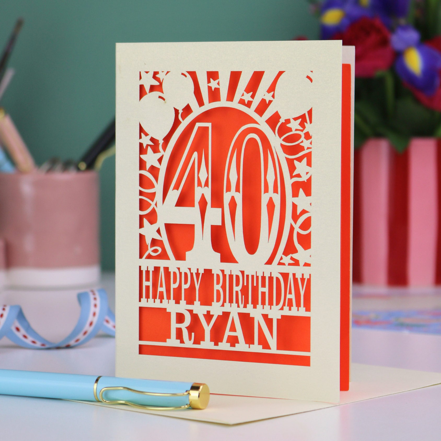 Personalized 40 birthday card with '40 Happy Birthday Ryan' on a desk with stationery items.