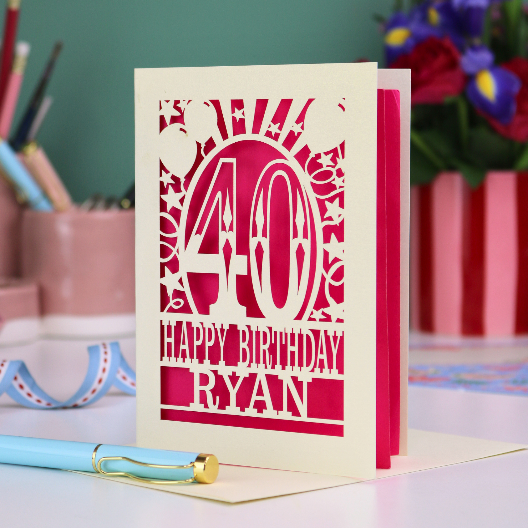 Personalized 40 birthday card with '40 Happy Birthday Ryan' on a desk with stationery items.