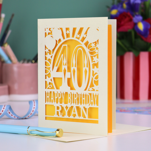 Personalized 40 birthday card with '40 Happy Birthday Ryan' on a desk with stationery items.