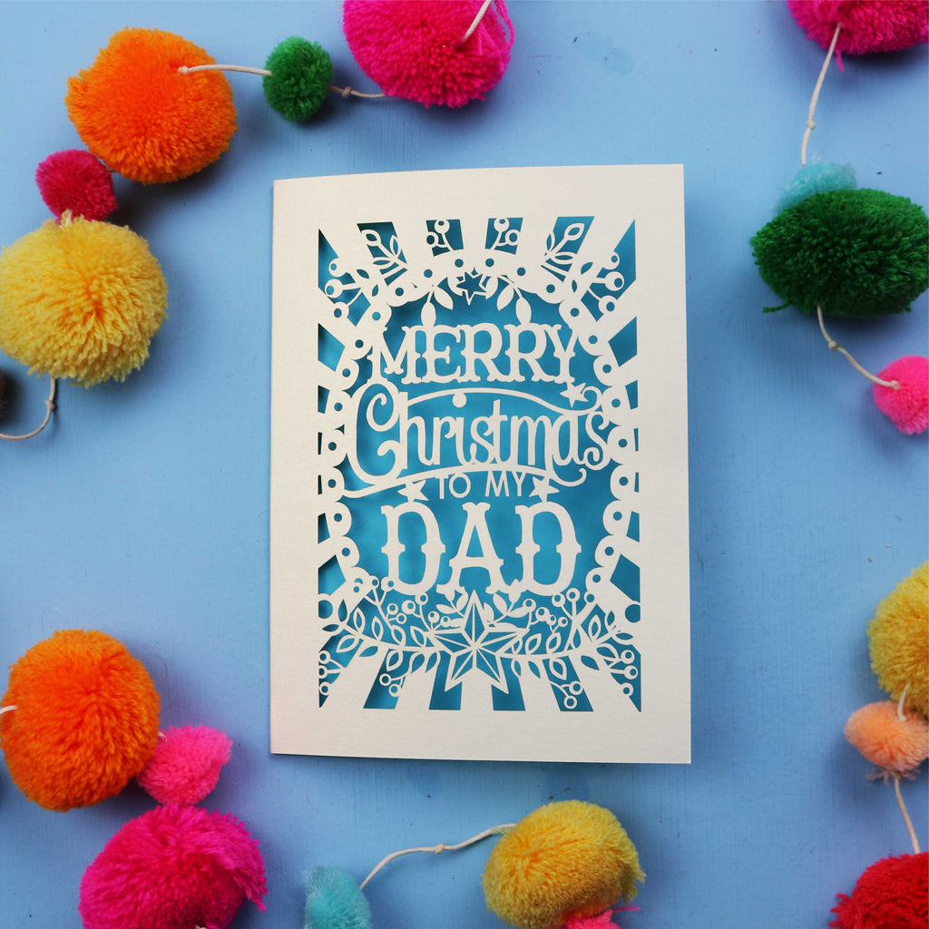 Dad Christmas card with 'Merry Christmas to my Dad' text on a blue background with colourful pom-poms.