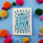 Dad Christmas card with 'Merry Christmas to my Dad' text on a blue background with colourful pom-poms.