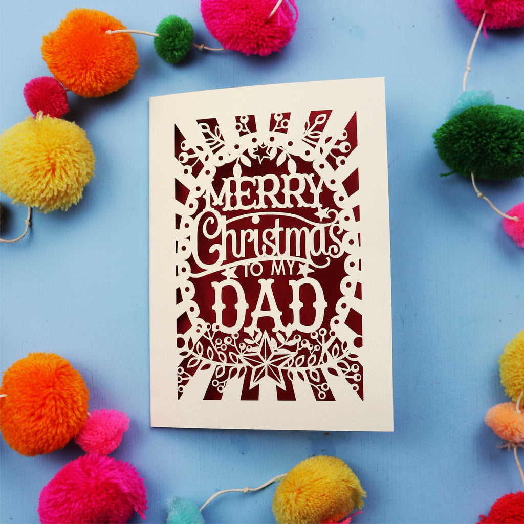 Dad Christmas card with 'Merry Christmas to my Dad' text on a blue background with colourful pom-poms.