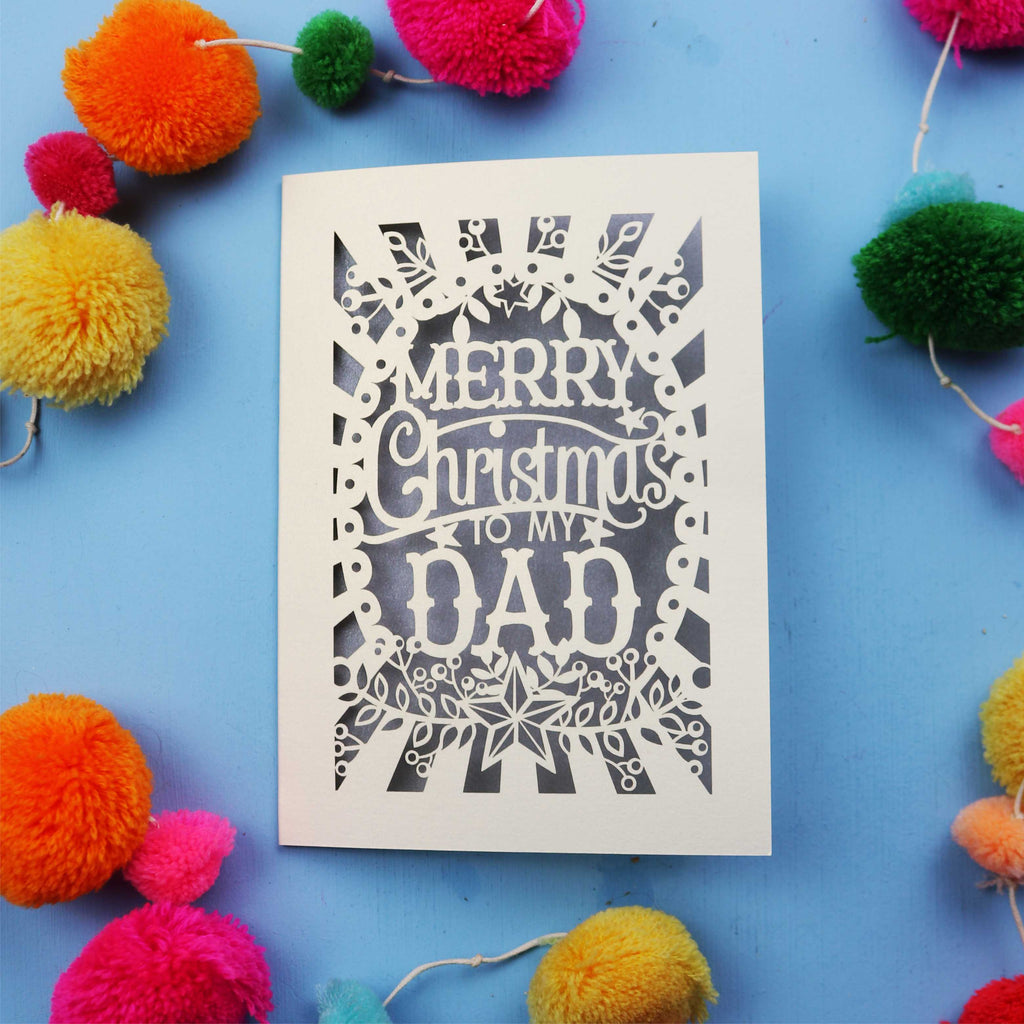 Dad Christmas card with 'Merry Christmas to my Dad' text on a blue background with colourful pom-poms.