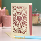 A cream laser cut grief card with cut out heart and flowers design and the text 'With Deepest Sympathy'