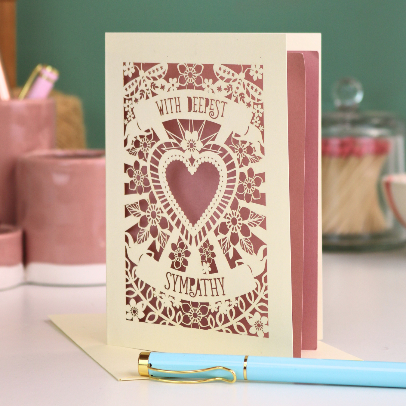 A cream laser cut grief card with cut out heart and flowers design and the text 'With Deepest Sympathy'