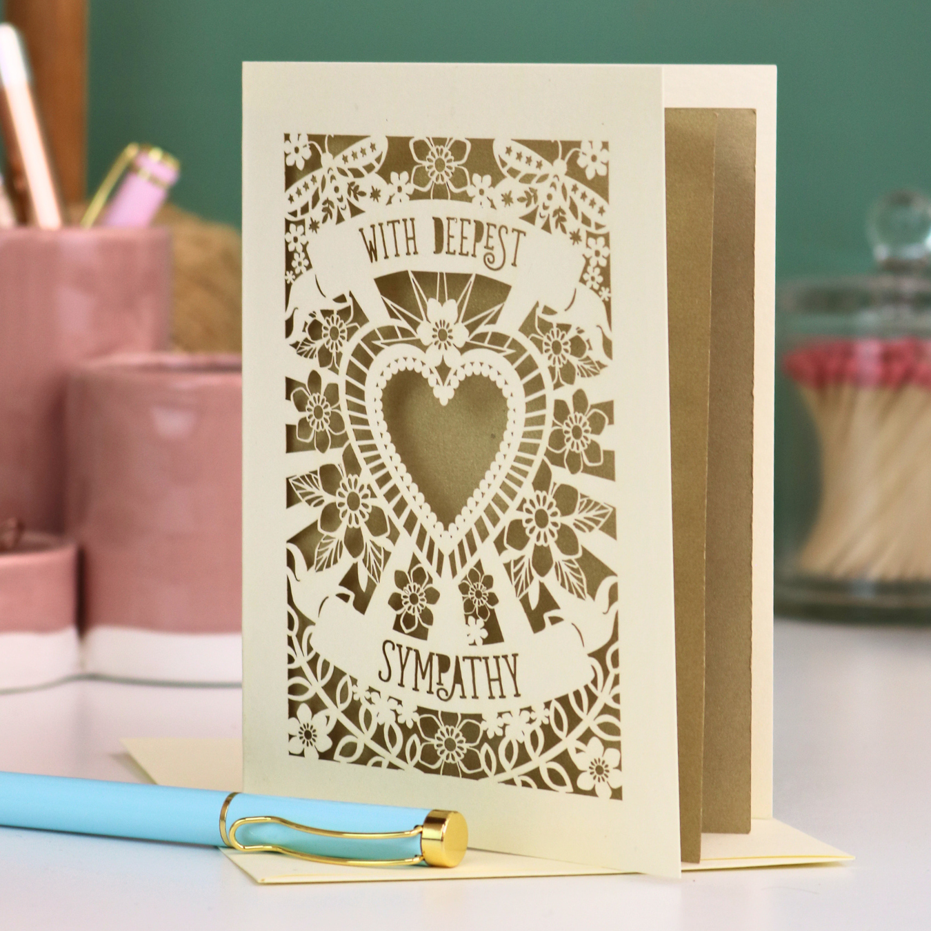 A cream laser cut loss card with cut out heart and flowers design and the text 'With Deepest Sympathy'