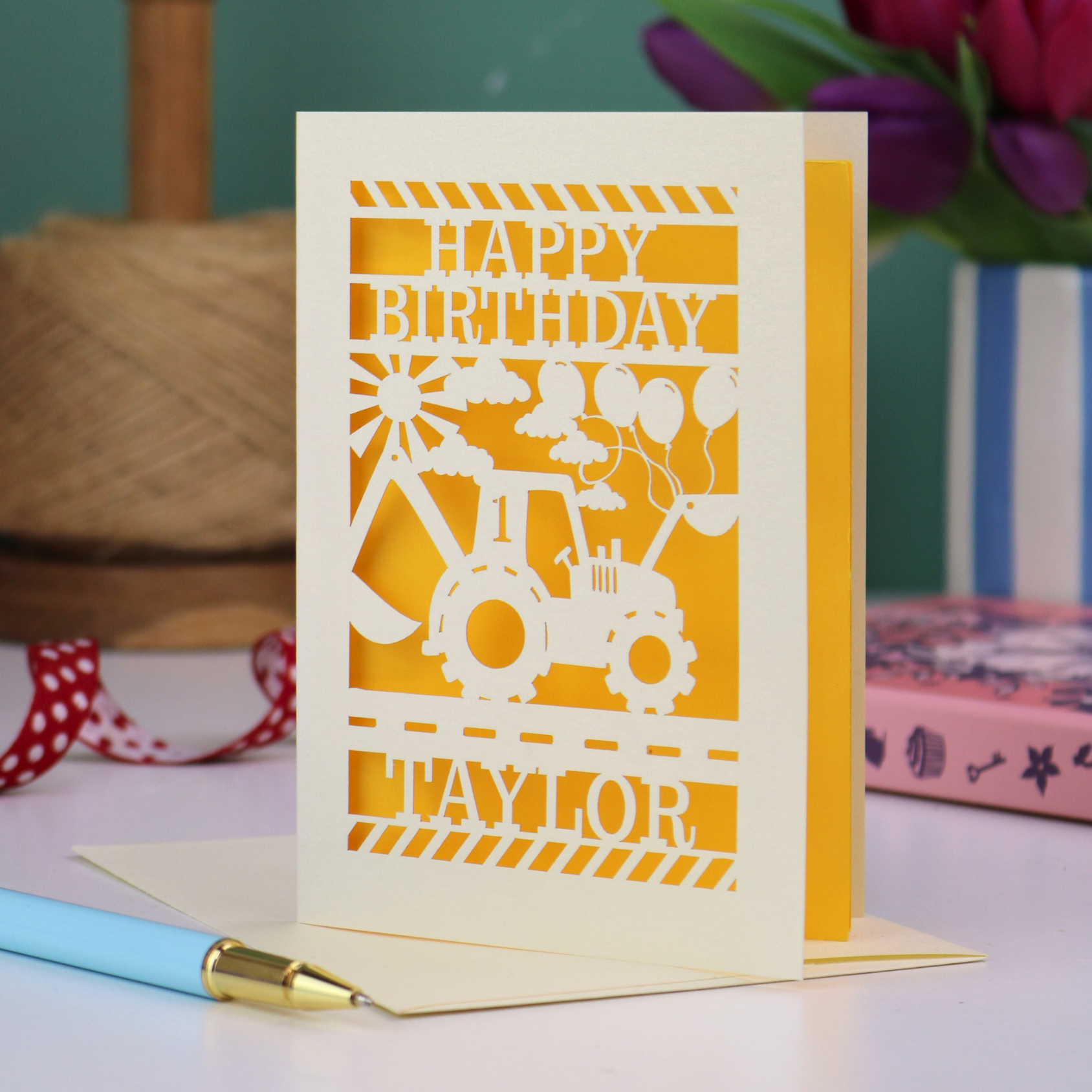 A laser cut first birthday card with cut out digger and "HAPPY BIRTHDAY TAYLOR" personalised text. 
