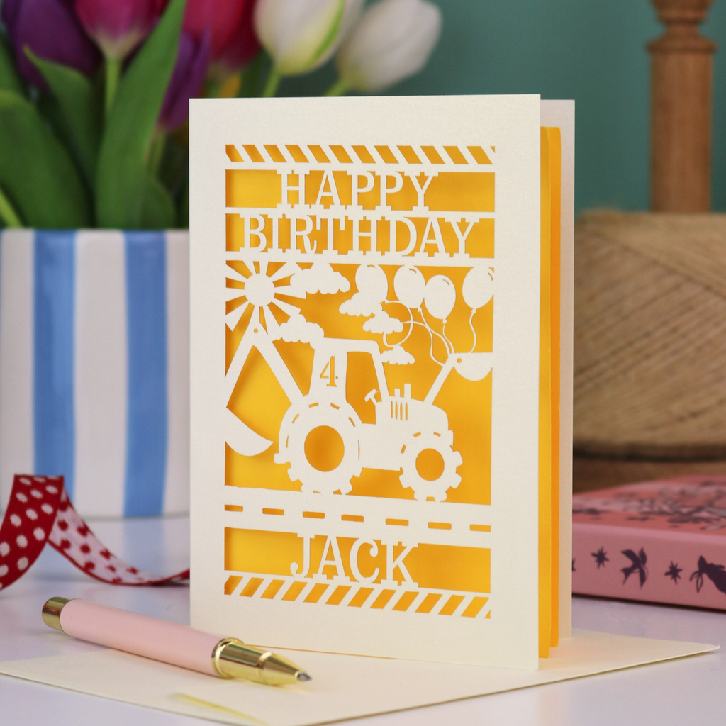 A kids' birthday card with laser cut digger design and "Happy Birthday" text, personalised with a name and age. 