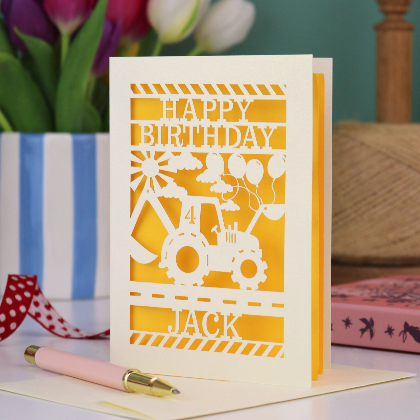 A kids' birthday card with laser cut digger design and "Happy Birthday" text, personalised with a name and age. 