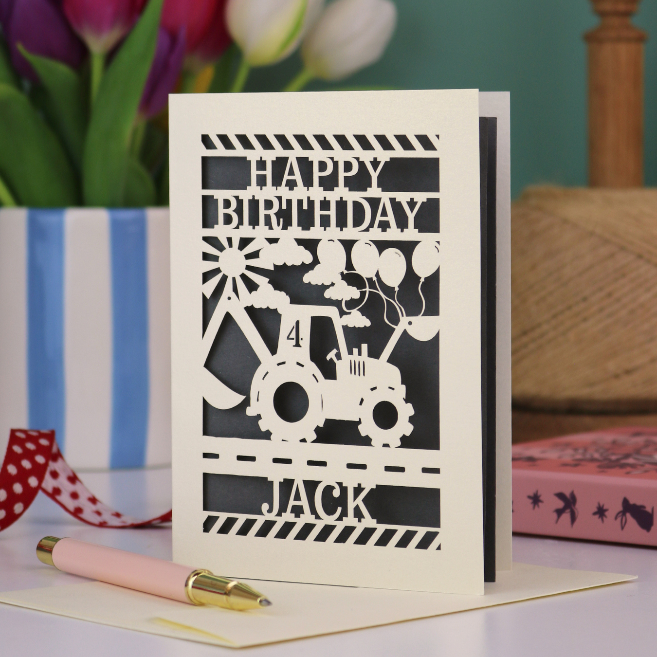 A kids' birthday card with laser cut tractor design and "Happy Birthday" text, personalised with a name and age. 