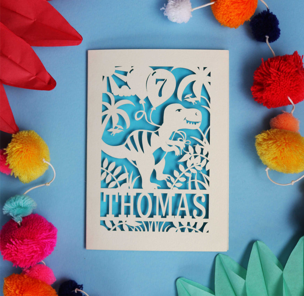 A laser cut dinosaur birthday card personalised with a name and age.