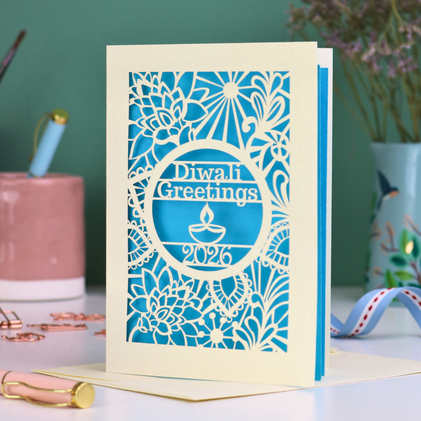 Laser Cut Diwali greetings card with intricate design and 'Diwali Greetings 2026' text on a desk.
