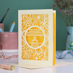 Laser Cut Diwali greetings card with intricate design and 'Diwali Greetings 2026' text on a desk.